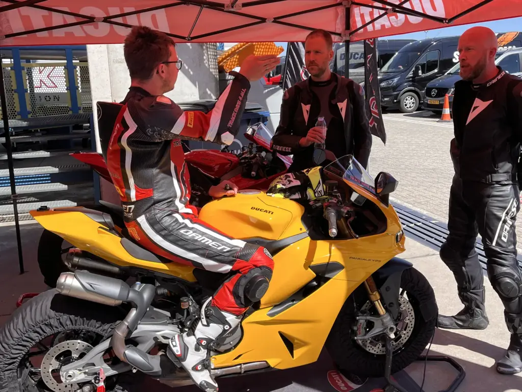 Rijders bij een gele Ducati onder de Ducati-tent in de paddock